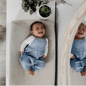 baby girl laying on changing pad and looking in the mirror
