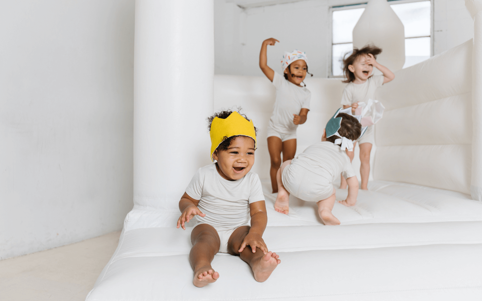 kids in a jumpy house wearing fabric 1st birthday crowns